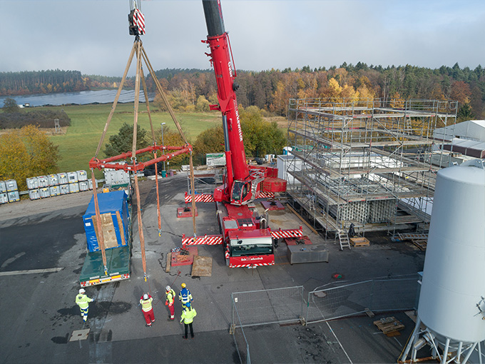 Kran hebt vorgefertigte Betonelemente auf einer Baustelle für ein Energie- und Industriegebäude