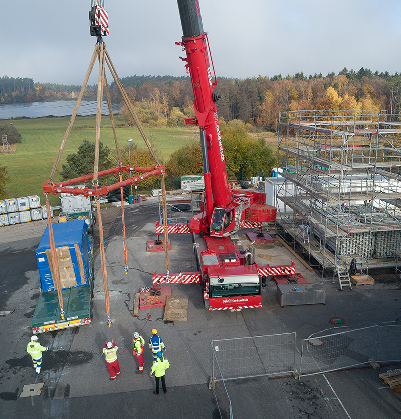 Kran hebt vorgefertigte Betonelemente auf einer Baustelle für ein Energie- und Industriegebäude