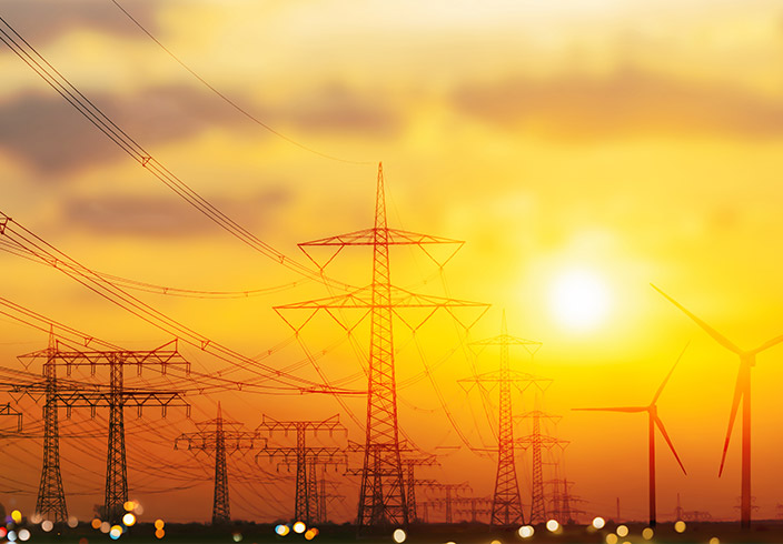 Strommasten mit Windrädern im Hintergrund